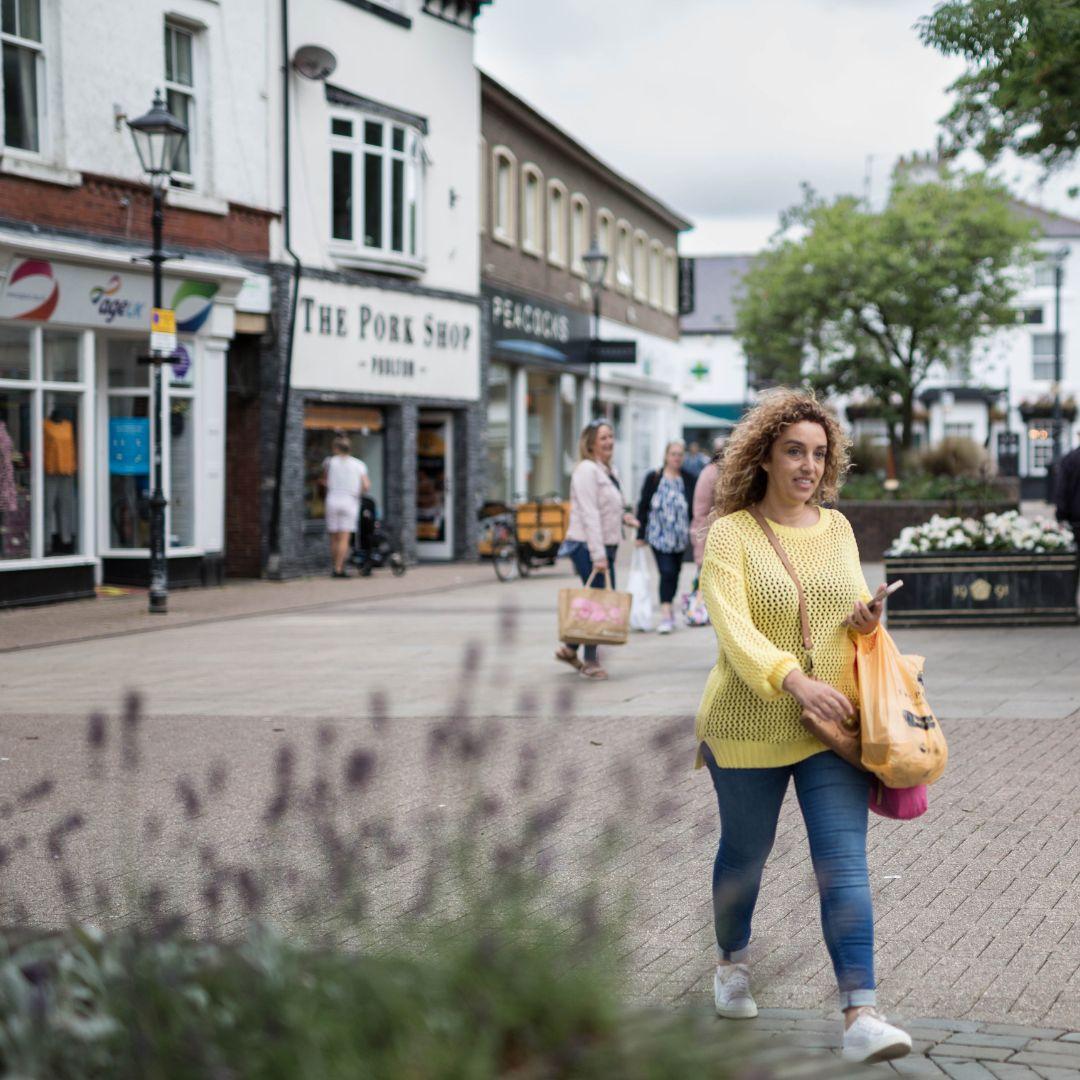 A young woman walks through a market town smiling