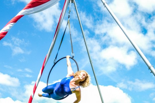 Acrobat performing outside against a clear blue sky