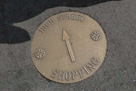 Brass plate in the pavement with &#039;High Street Shopping&#039; and an arrow pointing upwards