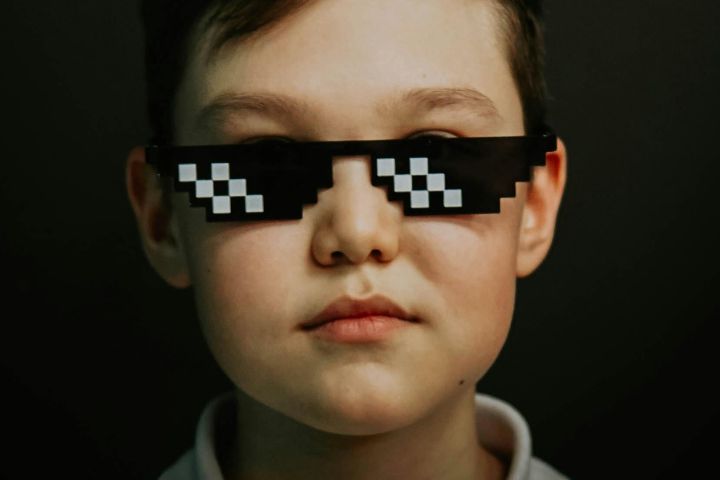 Child looking towards the camera wearing cartoon pixelated glasses