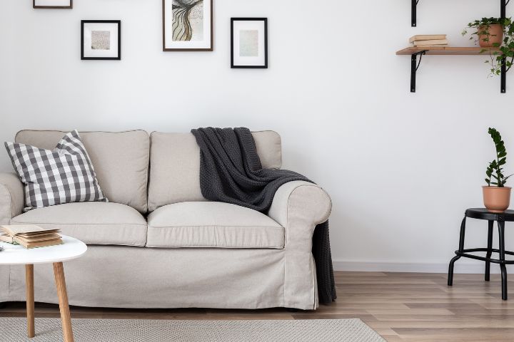 Image of furniture in a typical sitting room, including a sofa, side tables and photos on the wall.