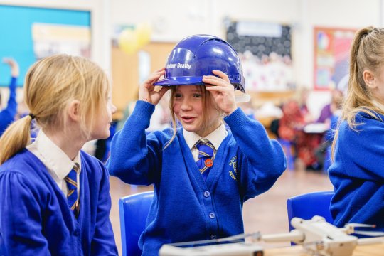 Children in school uniform. One is wearing a blue builders hat