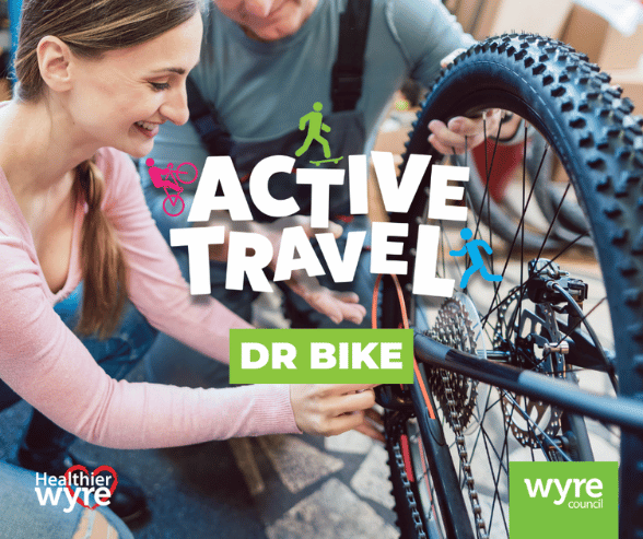 Active Travel - Dr bike. Two smiling people looking at the gears and wheel on the rear tire of a bike.