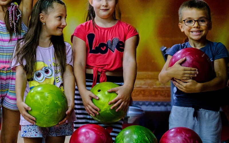 Kids in a row holding bowling balls.