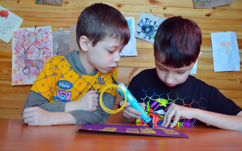 Two young boys at a table taking part in arts and crafts.